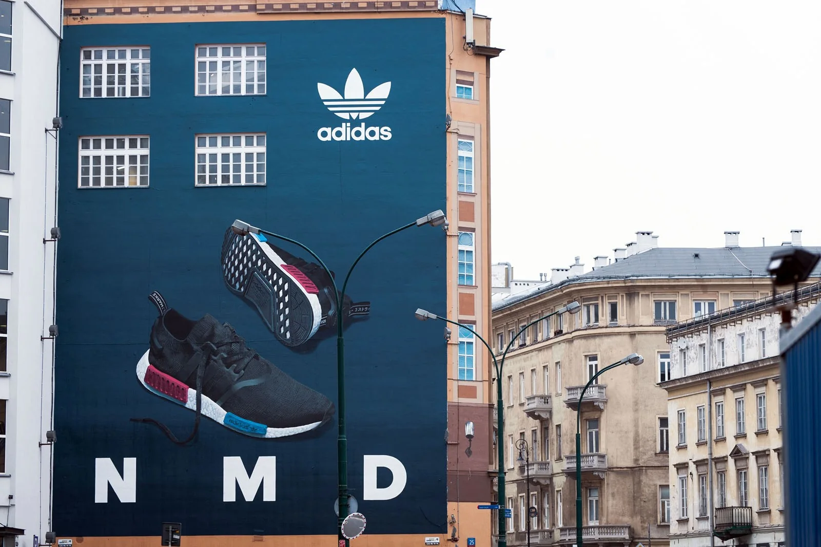 Mural adidas Originals NMD z butem na fasadzie kamienicy przy Brackiej, w dzień