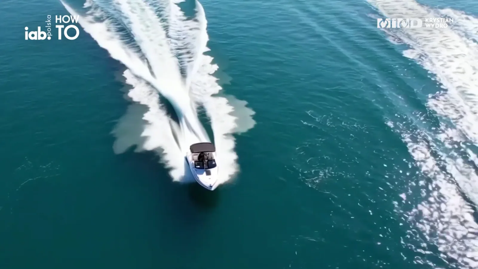 A speedboat on a turquoise sea, seen from a drone