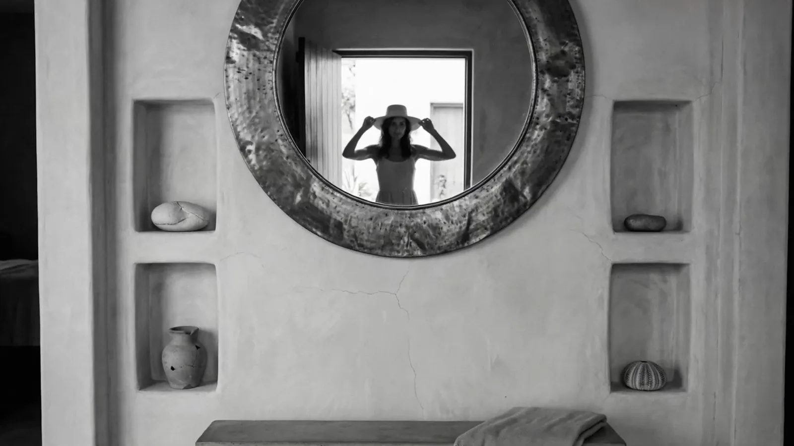 A woman in a hat reflected in a round mirror
